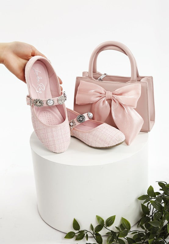 Pink Mary Janes with embellished straps and pearl charms, paired with a matching bow bag
