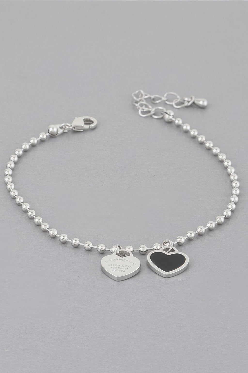 Love bracelet mit silberner Perlenkette und zwei Herzanhängern, davon einer dunkel umrandet