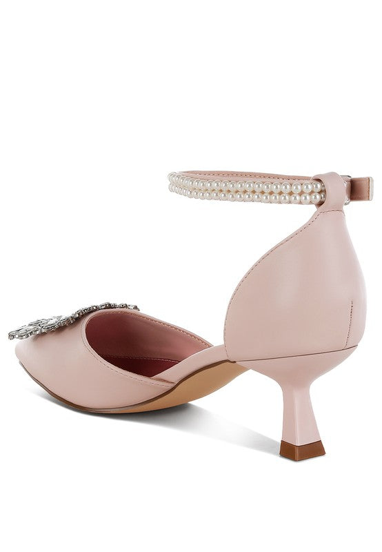 Pink kitten-heel sandal heel view with rhinestone brooch and beaded ankle band