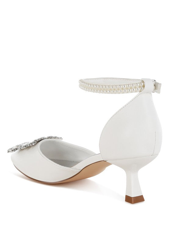 White kitten-heel sandal back view with ankle strap and rhinestone brooch detail