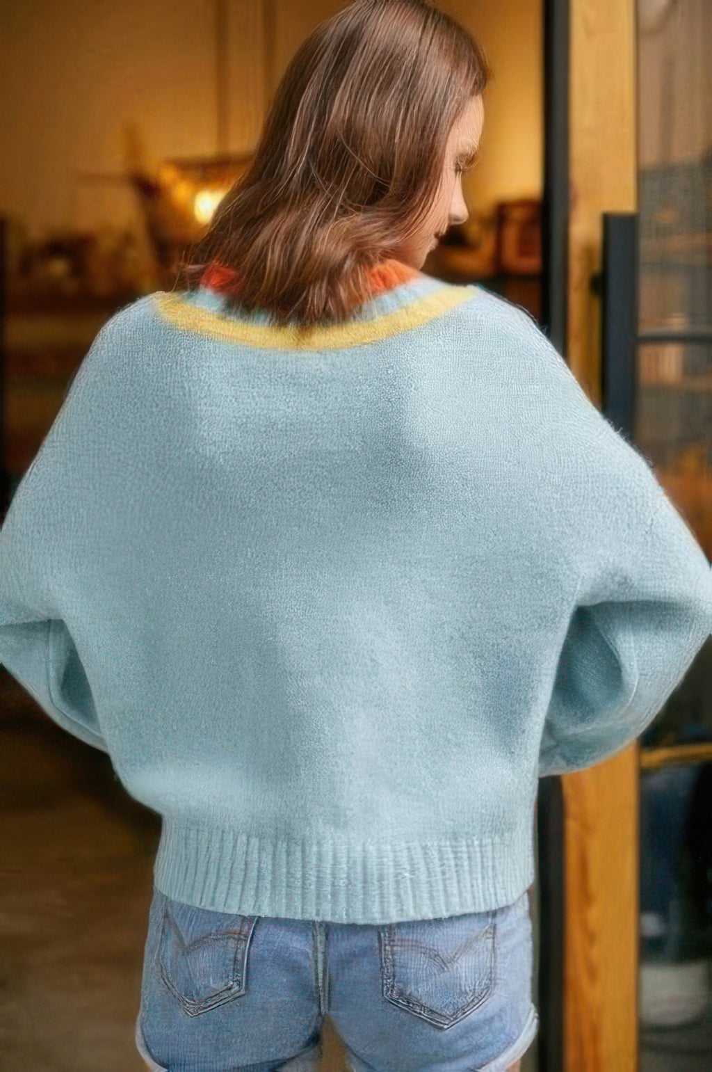 Back view of light blue overlap V-neck sweater with striped neckline rib trim