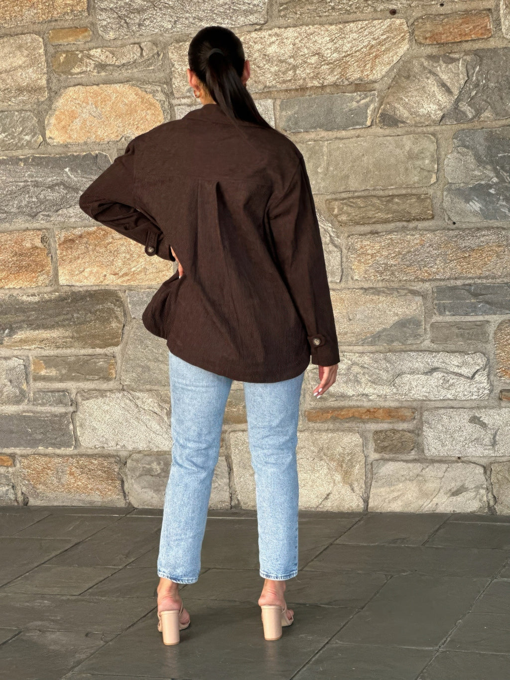 Back view of oversized dark brown corduroy shacket with button closure at cuffs
