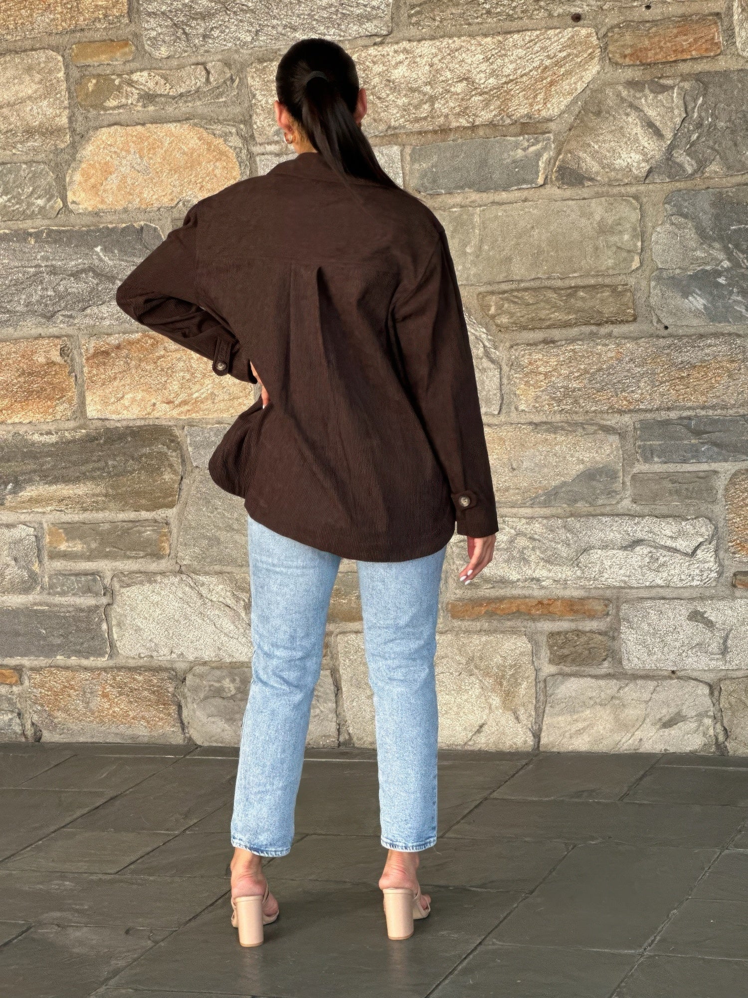 Back view of oversized dark brown corduroy shacket with button closure at cuffs