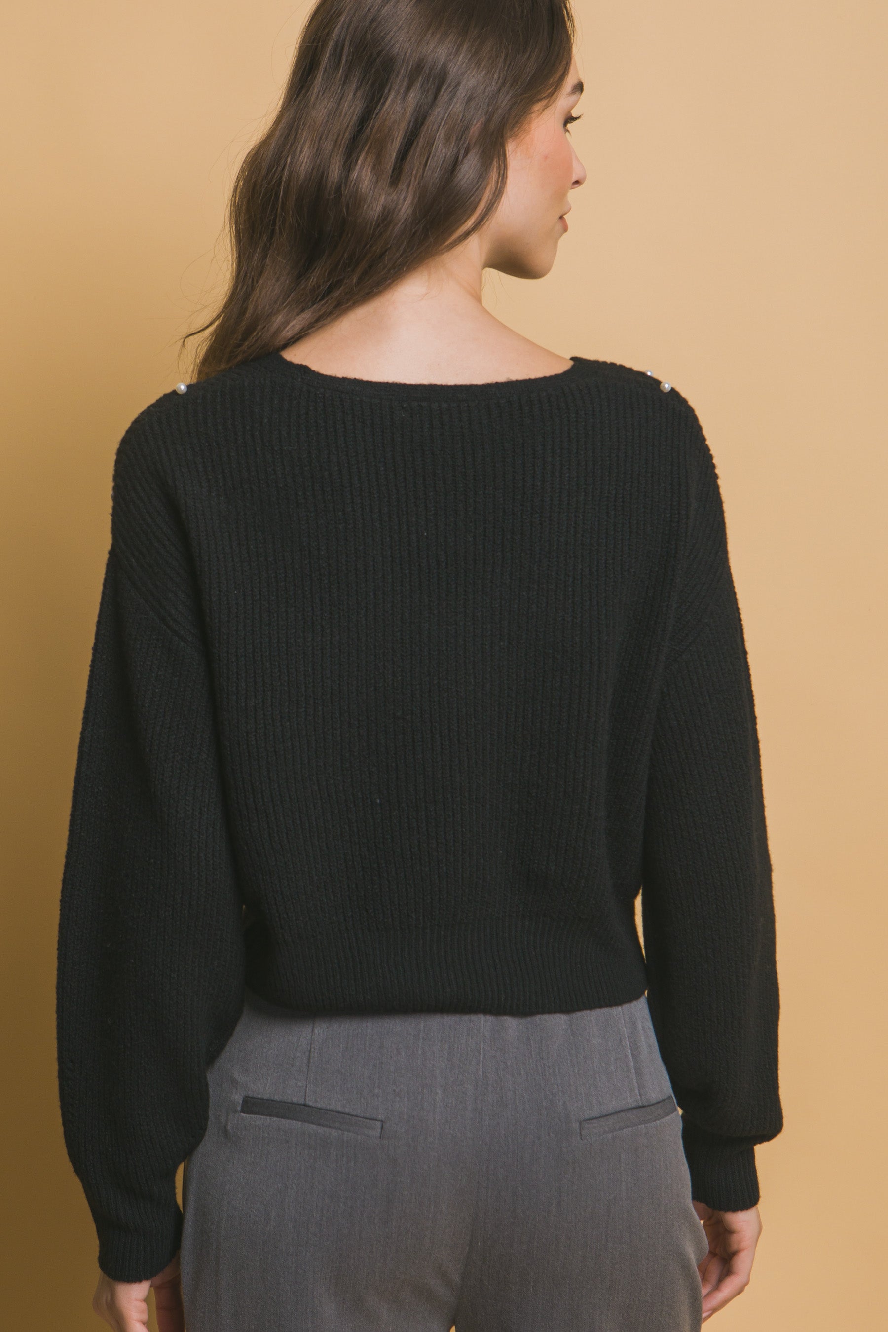 Black knit sweater back view with ribbed crew neck and cuffs