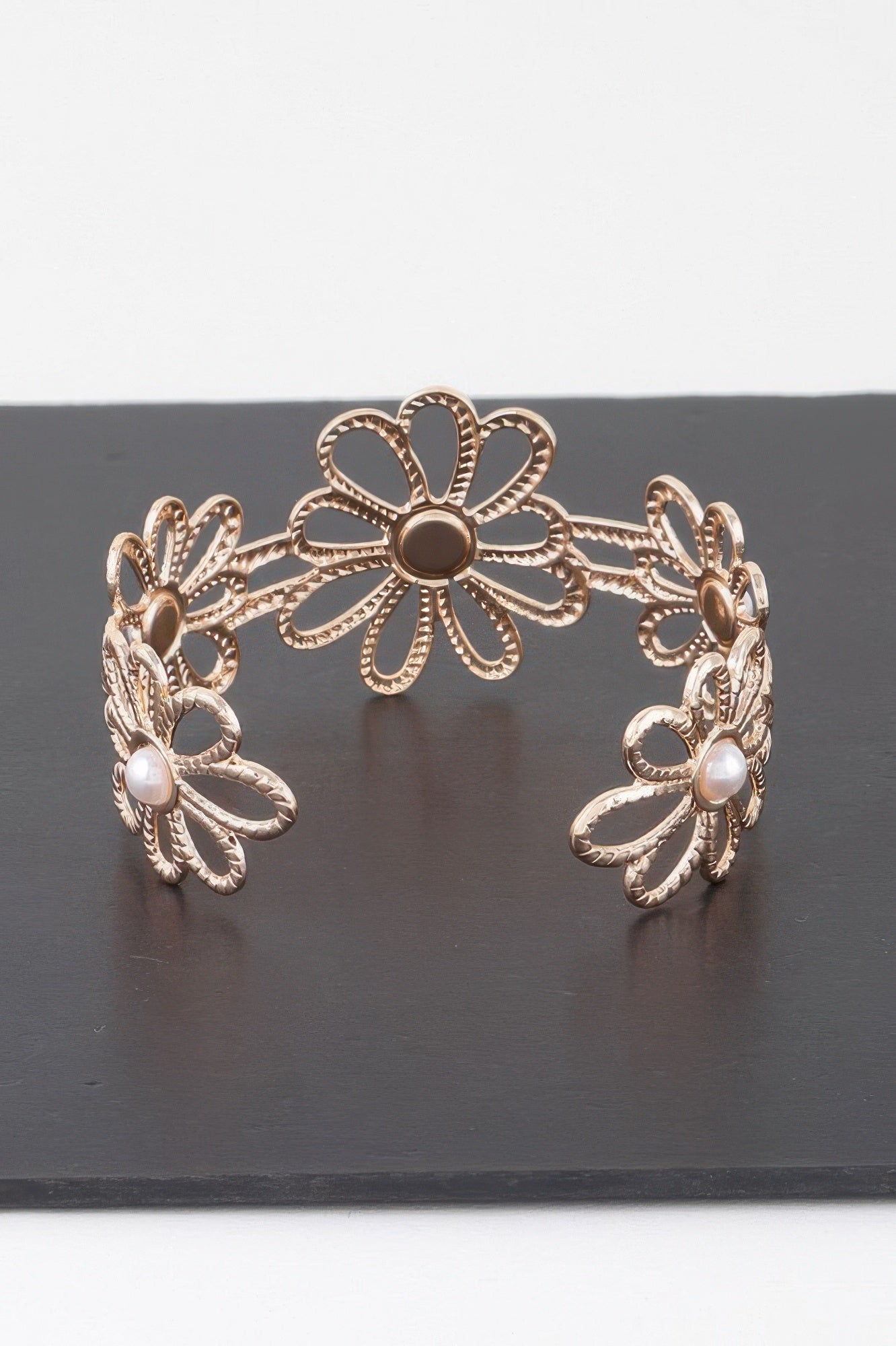 Gold-tone flower cuff bracelet with three daisy motifs and small pearl beads
