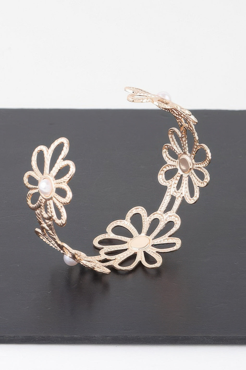 Gold-tone cuff bracelet with five-petal flower designs and round pearl centers