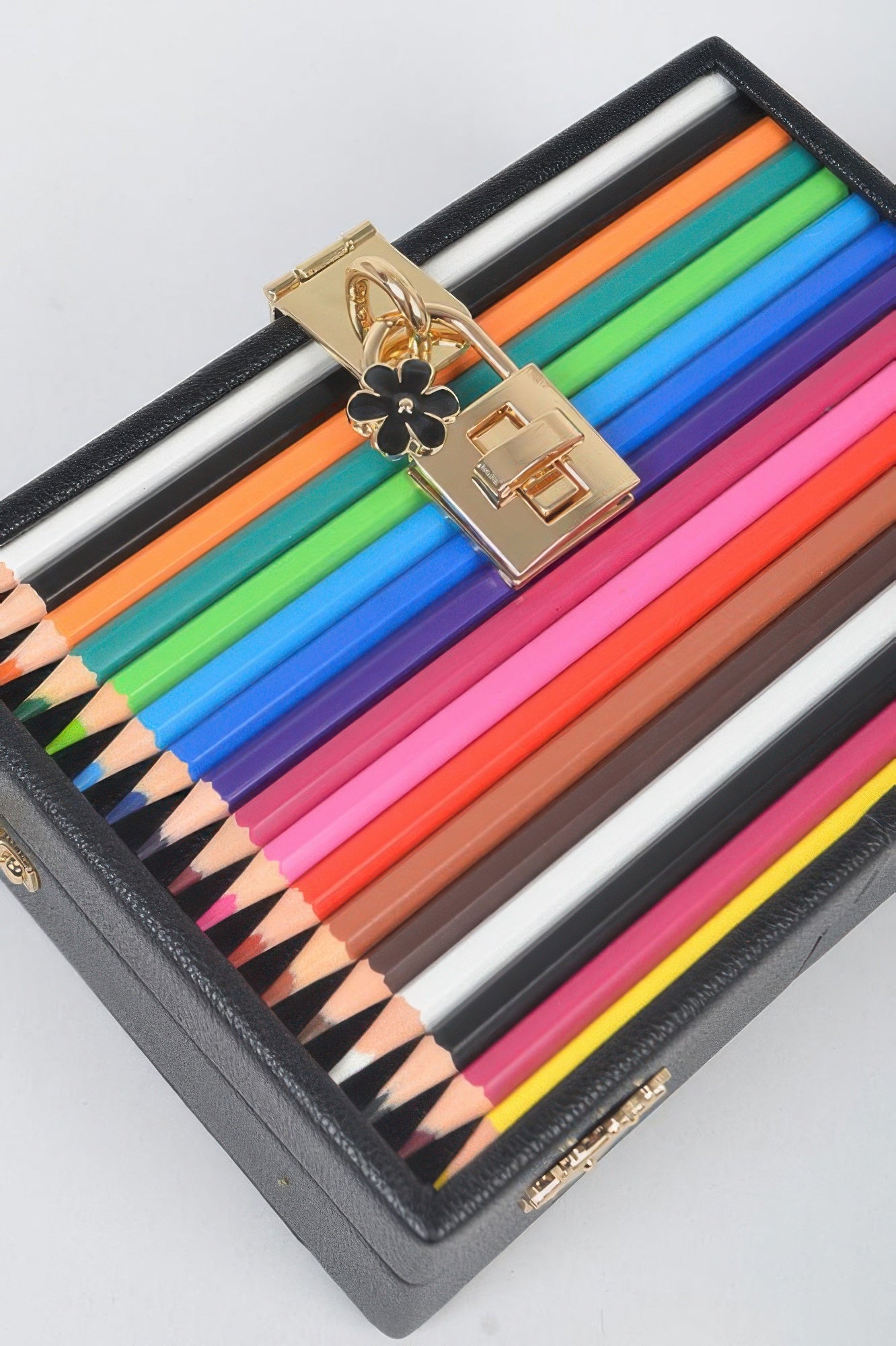 Lock-and-key detail on black pencil case clutch with multicolor pencils