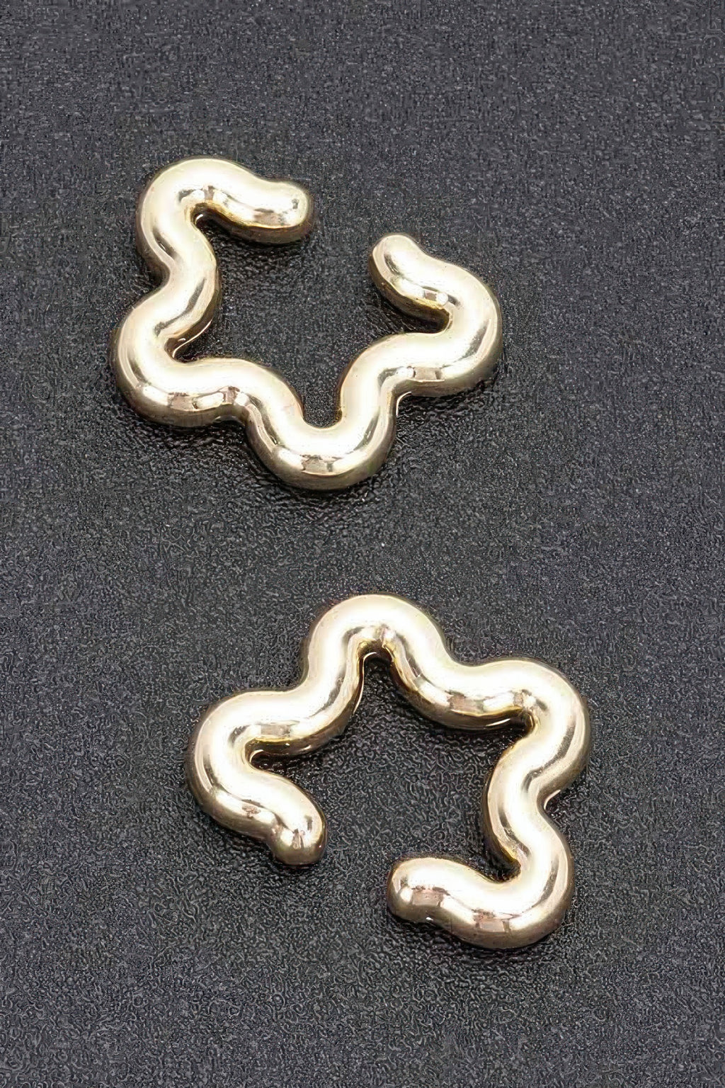 Gold plastic cuff earrings with smooth wavy pattern and open cuff shape