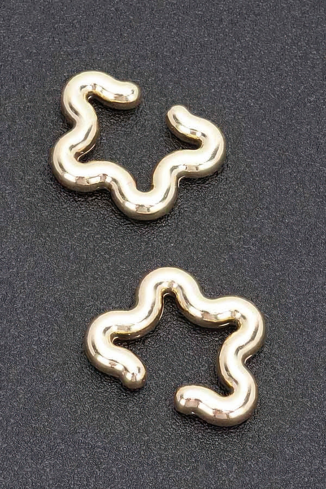 Gold plastic cuff earrings with smooth wavy pattern and open cuff shape