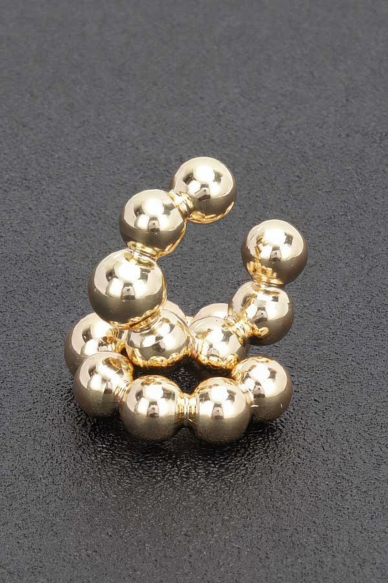 Gold plastic cuff hoop earring with glossy bead spheres around the curve