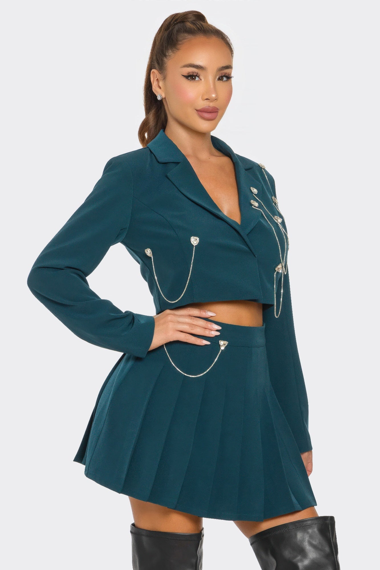 Teal pleated skirt set featuring cropped blazer with lapel and silver chain ornaments