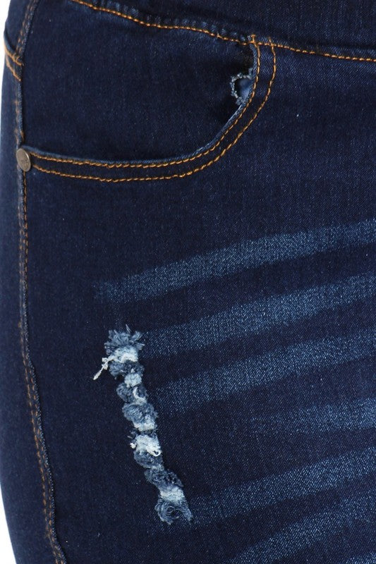 Close-up of medium blue denim jeggings: ripped knee detail and contrast stitching