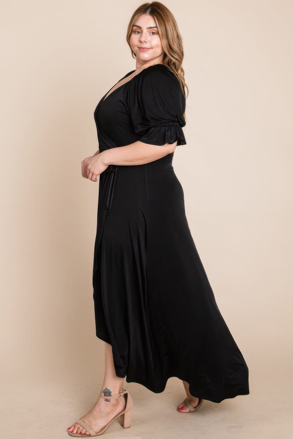Side view of black faux wrap maxi dress with puff sleeves and tie waist