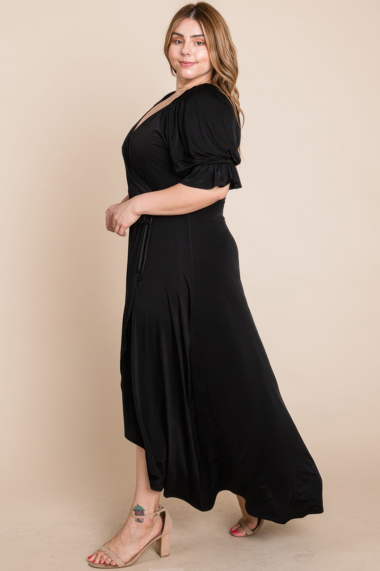 Side view of black faux wrap maxi dress with puff sleeves and tie waist
