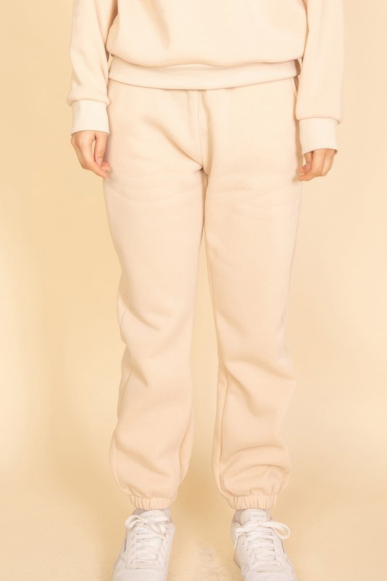Cream poly fleece joggers with elastic waist and gathered ankle cuffs