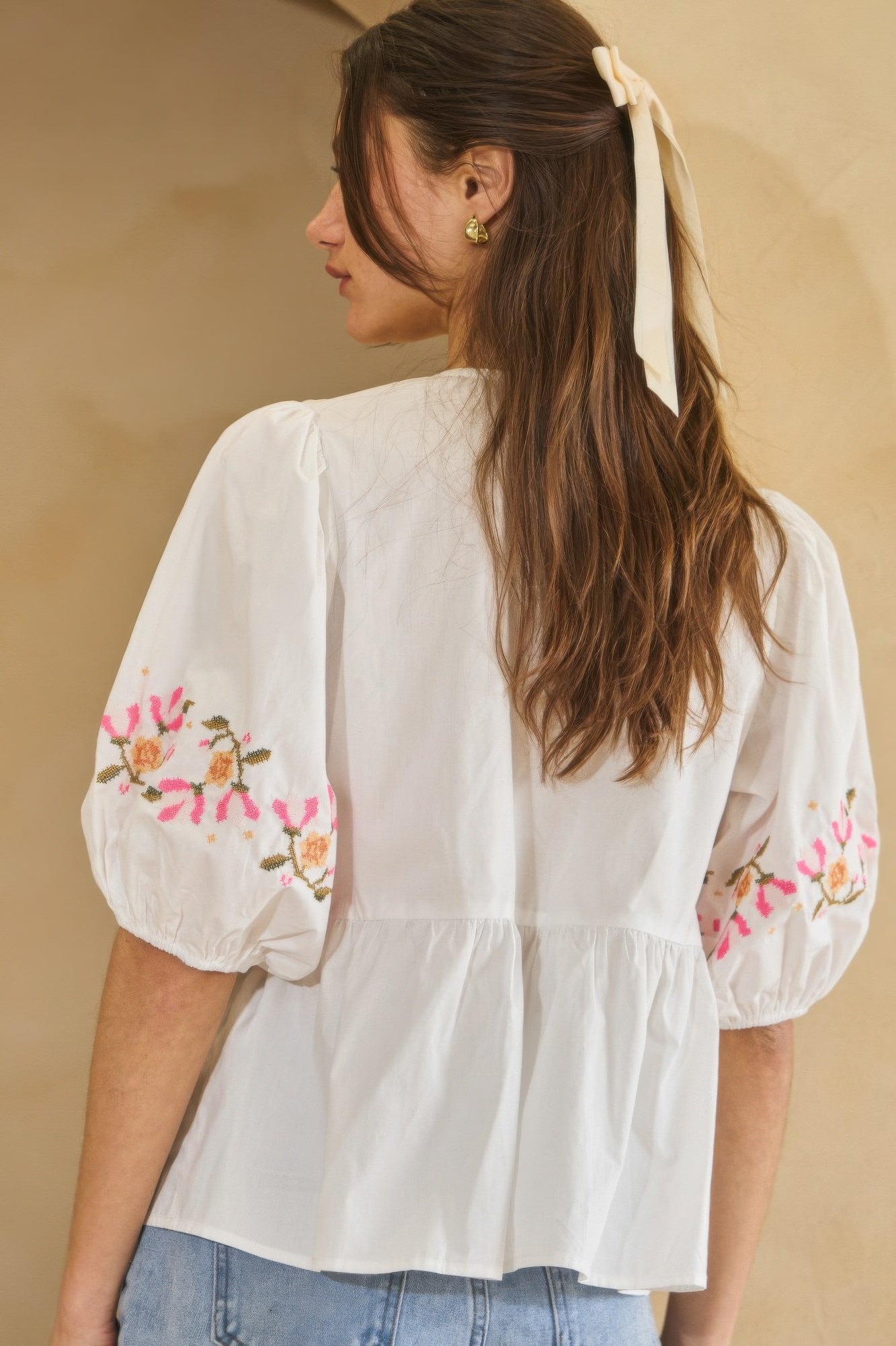 Off-white poplin blouse with embroidered floral cuffs and gathered peplum waist