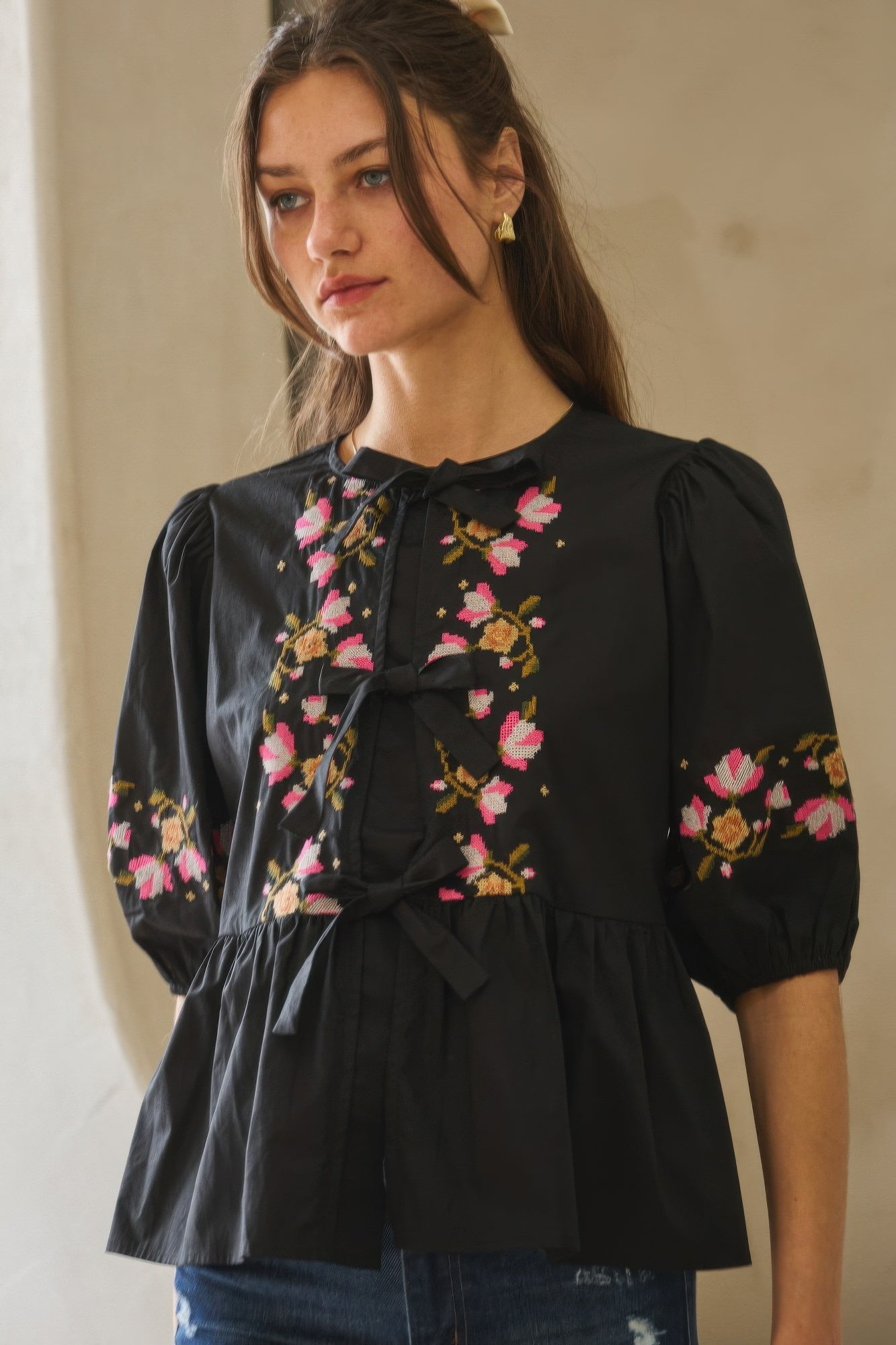 Black peplum-style blouse with floral embroidery and bow front tie, puff sleeves