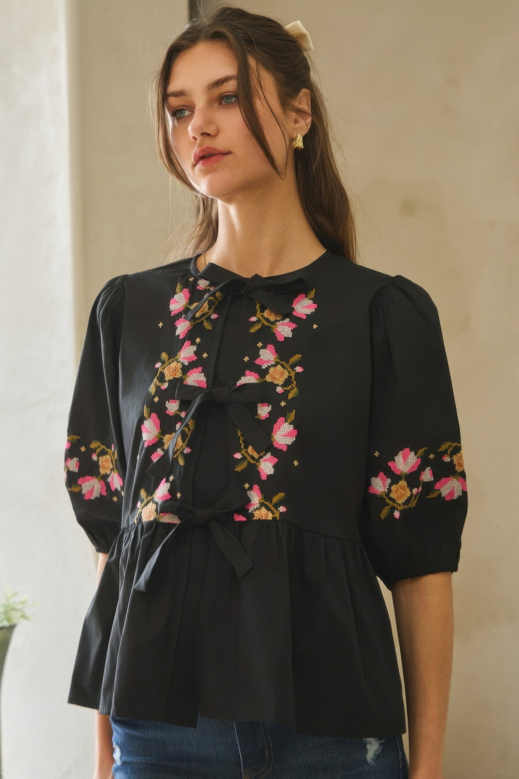 Front view: black poplin blouse with floral embroidery and ribbon bow tie at neckline