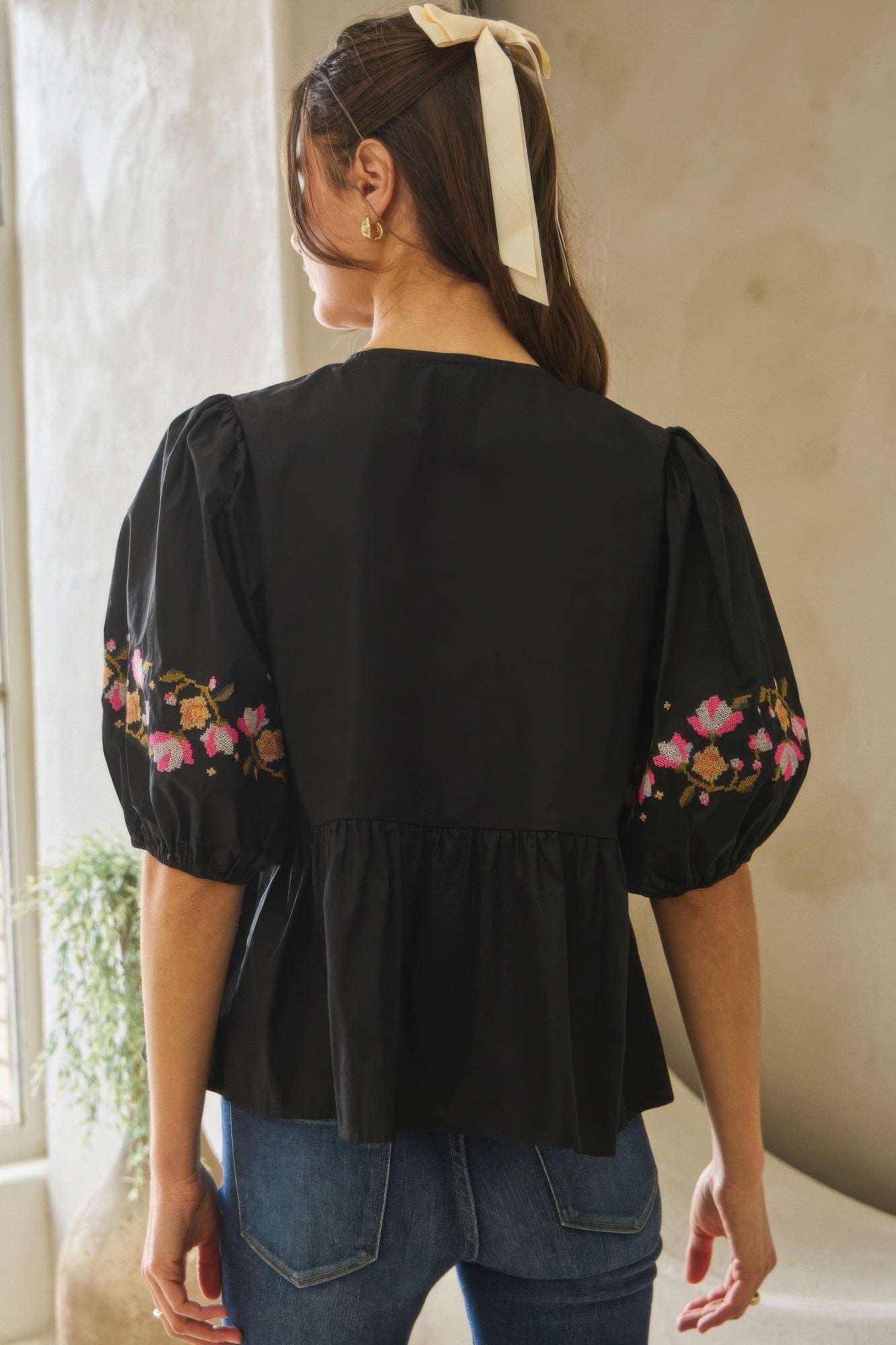 Back view: black poplin blouse with floral embroidery on sleeves and peplum waist