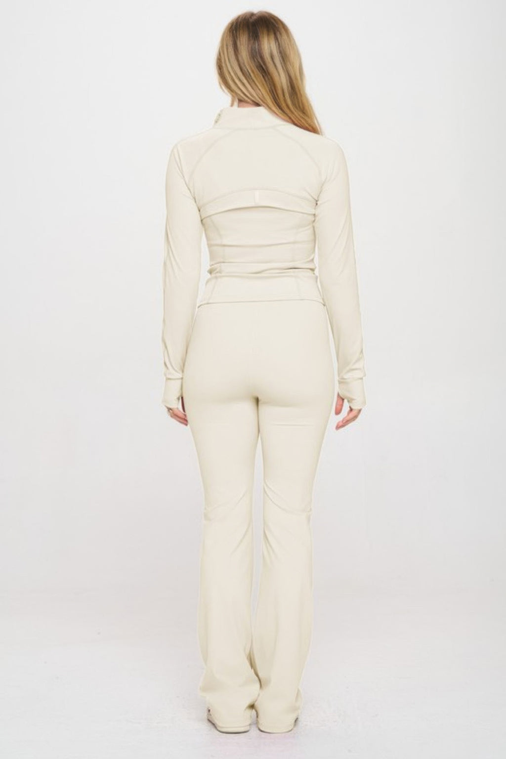 Back view: cream yoga jumpsuit set with zip jacket and ruched waist detail