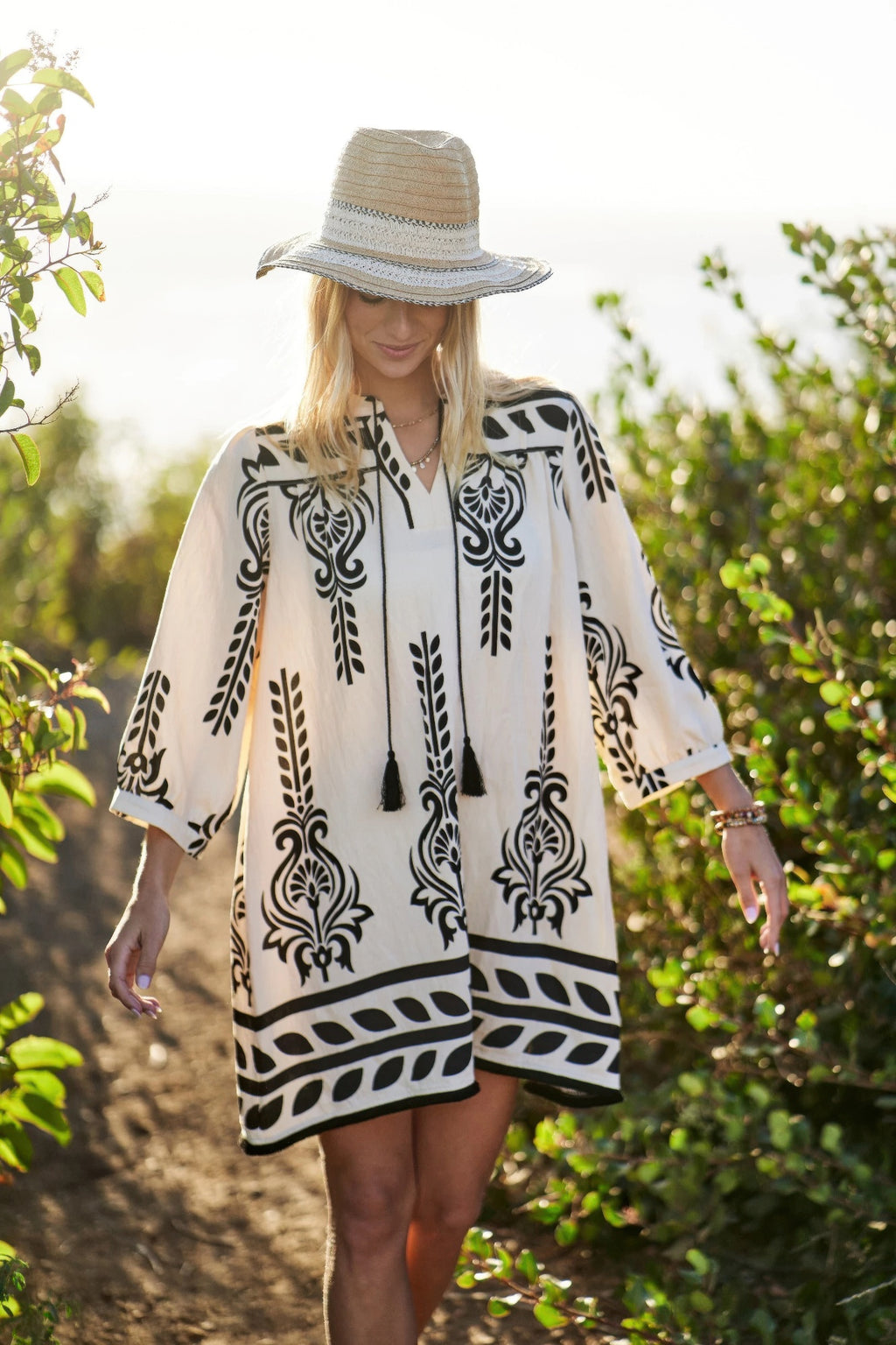 Cream printed dress with black geometric motifs and tassel tie at the neckline
