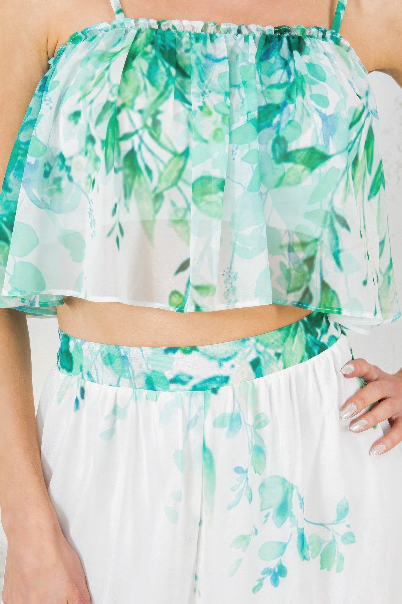 Close-up: green leafy print ruffle crop top with elastic neckline on white