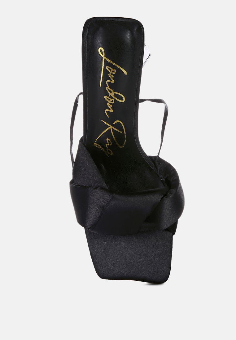 Black satin slide sandal with triangular block heel and ankle ties; gold script logo