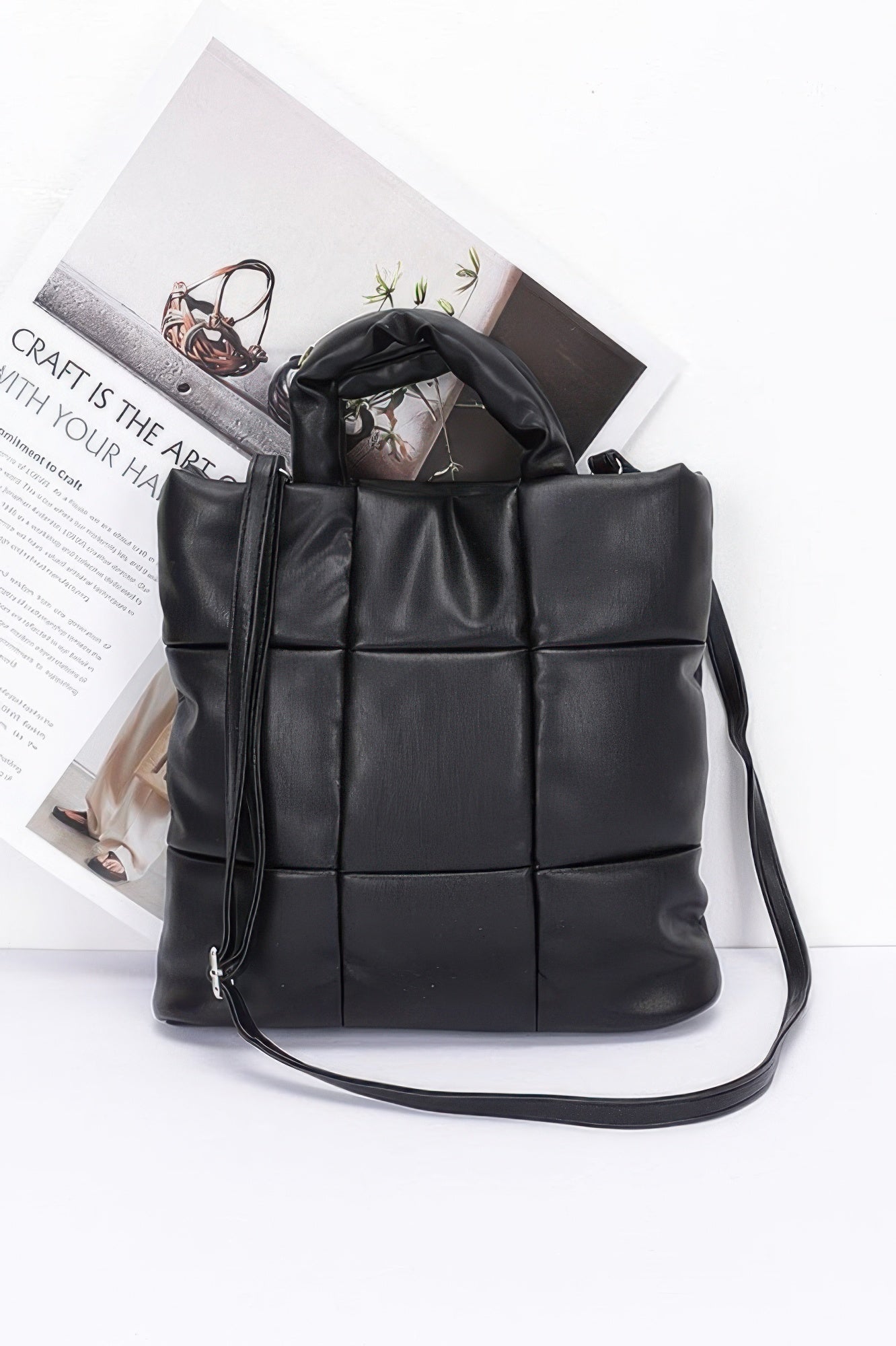 Black quilted padded tote bag with top handles and long shoulder strap