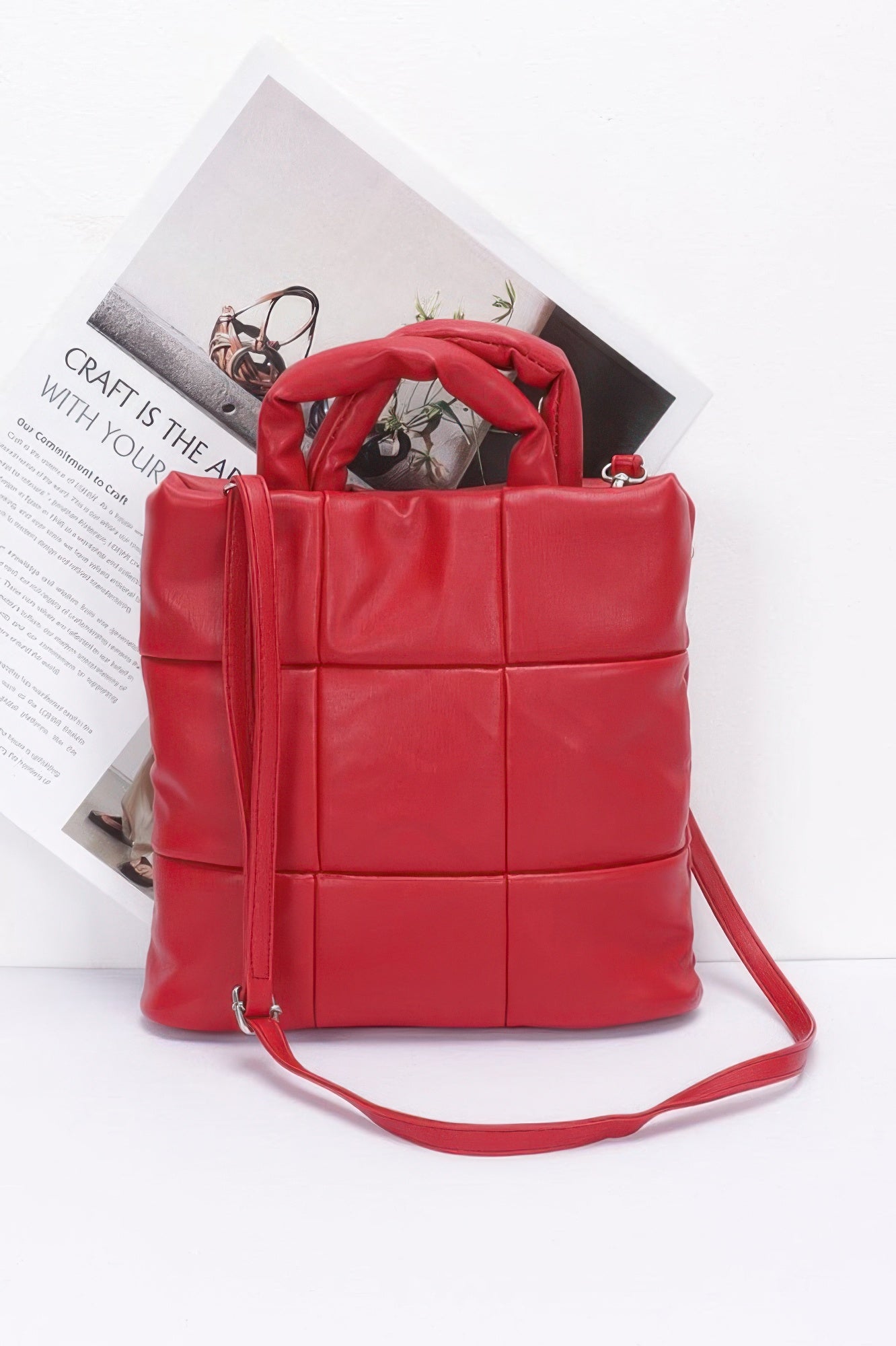 Red quilted faux leather padded tote bag with top handles and matching shoulder strap