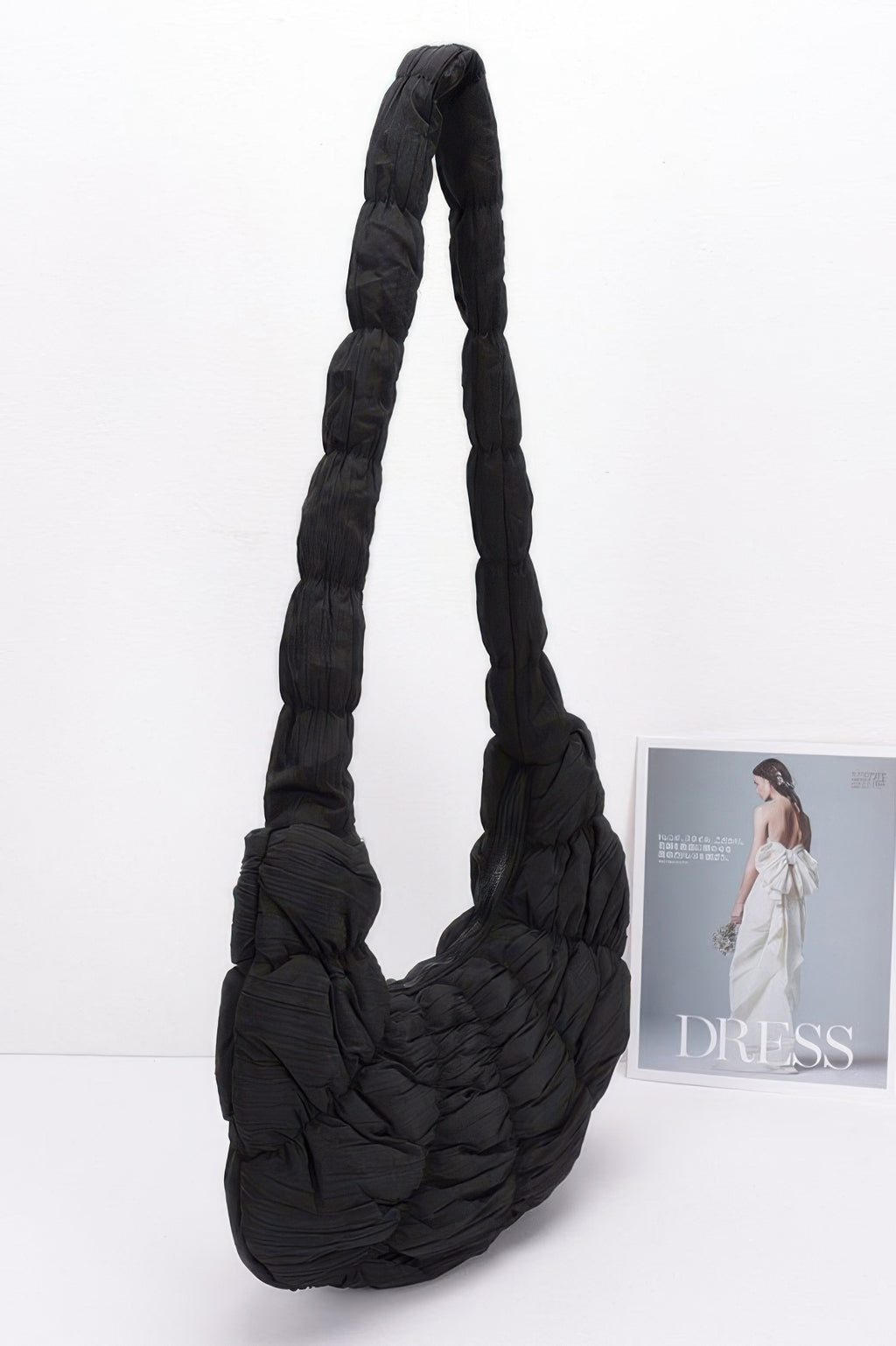 Black quilted nylon padded crossbody bag with long carry strap and rounded body