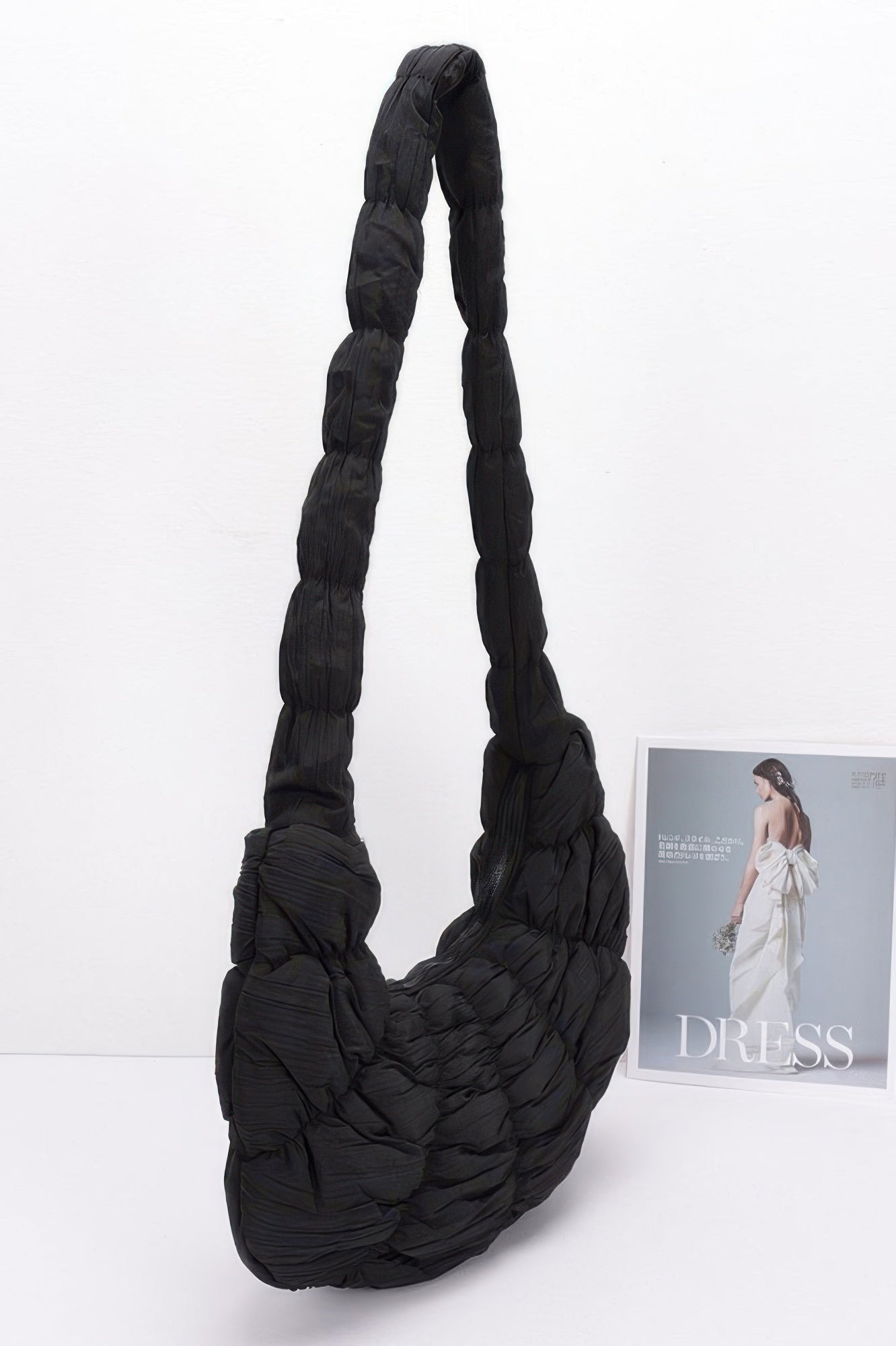 Black quilted nylon padded crossbody bag with long carry strap and rounded body