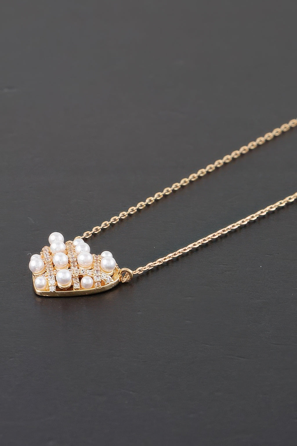 Close-up gold pearl heart pendant with quilted pattern and clustered white pearls