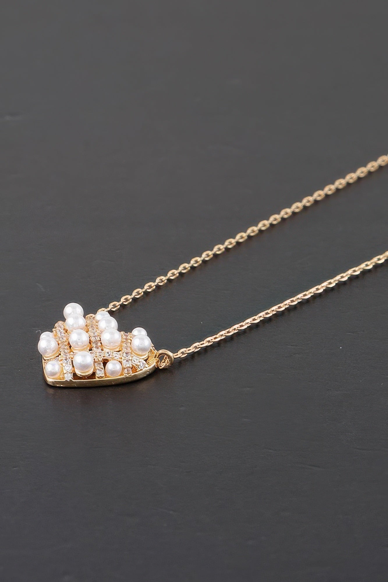Close-up gold pearl heart pendant with quilted pattern and clustered white pearls