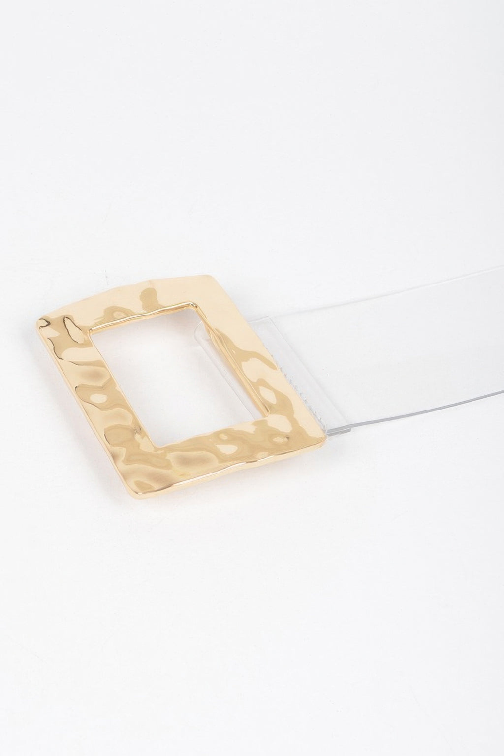 Gold rectangular metal buckle detail with open center, laid on clear strap