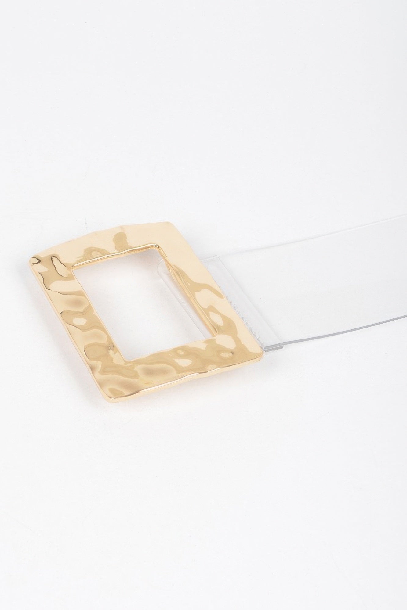 Gold rectangular metal buckle detail with open center, laid on clear strap