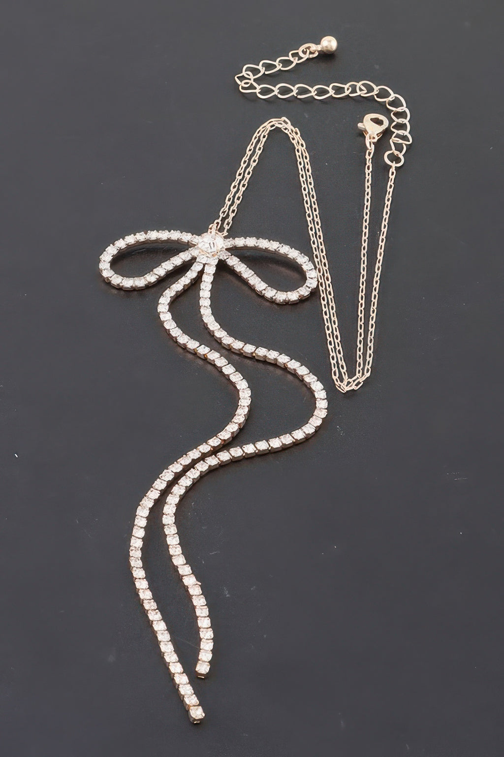 Rhinestone bow necklace with clear rhinestone bow and layered chain drops.