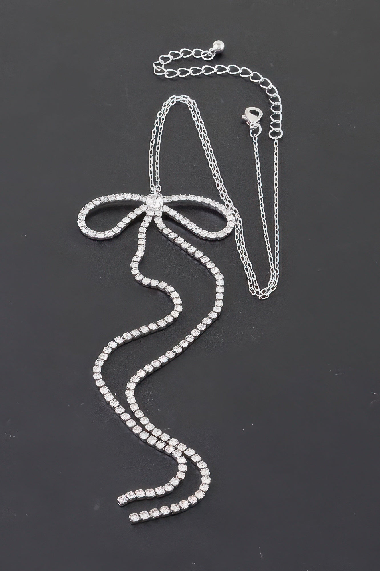 Rhinestone bow necklace: clear rhinestone bow with long vertical chain strands.