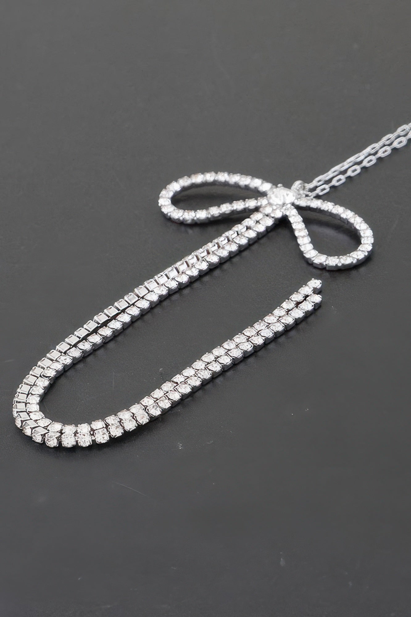 Close-up: clear rhinestone bow detail with sparkling chain links.