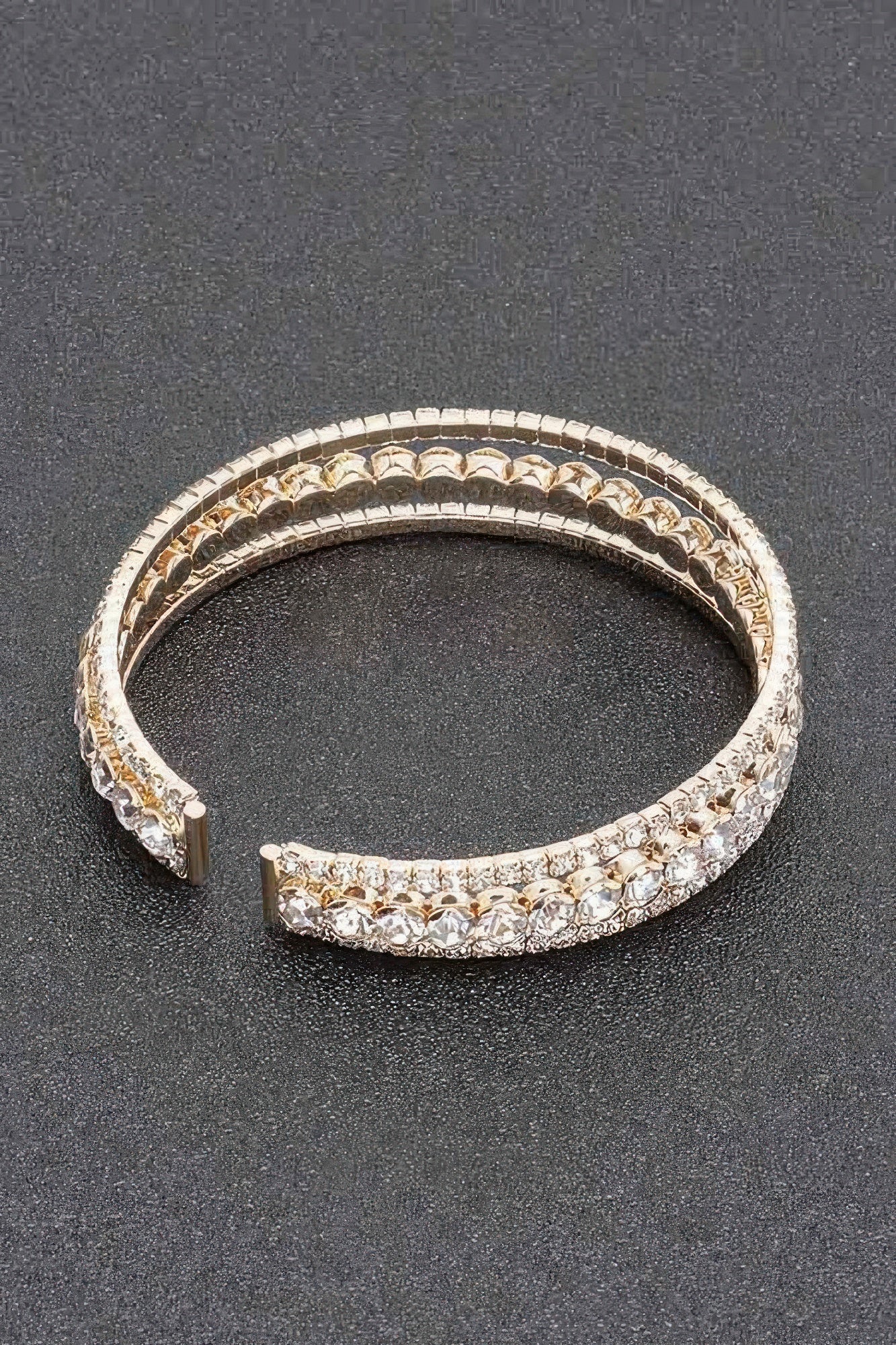Rhinestone bracelet with gold-toned band, clear stones, hinged clasp detail