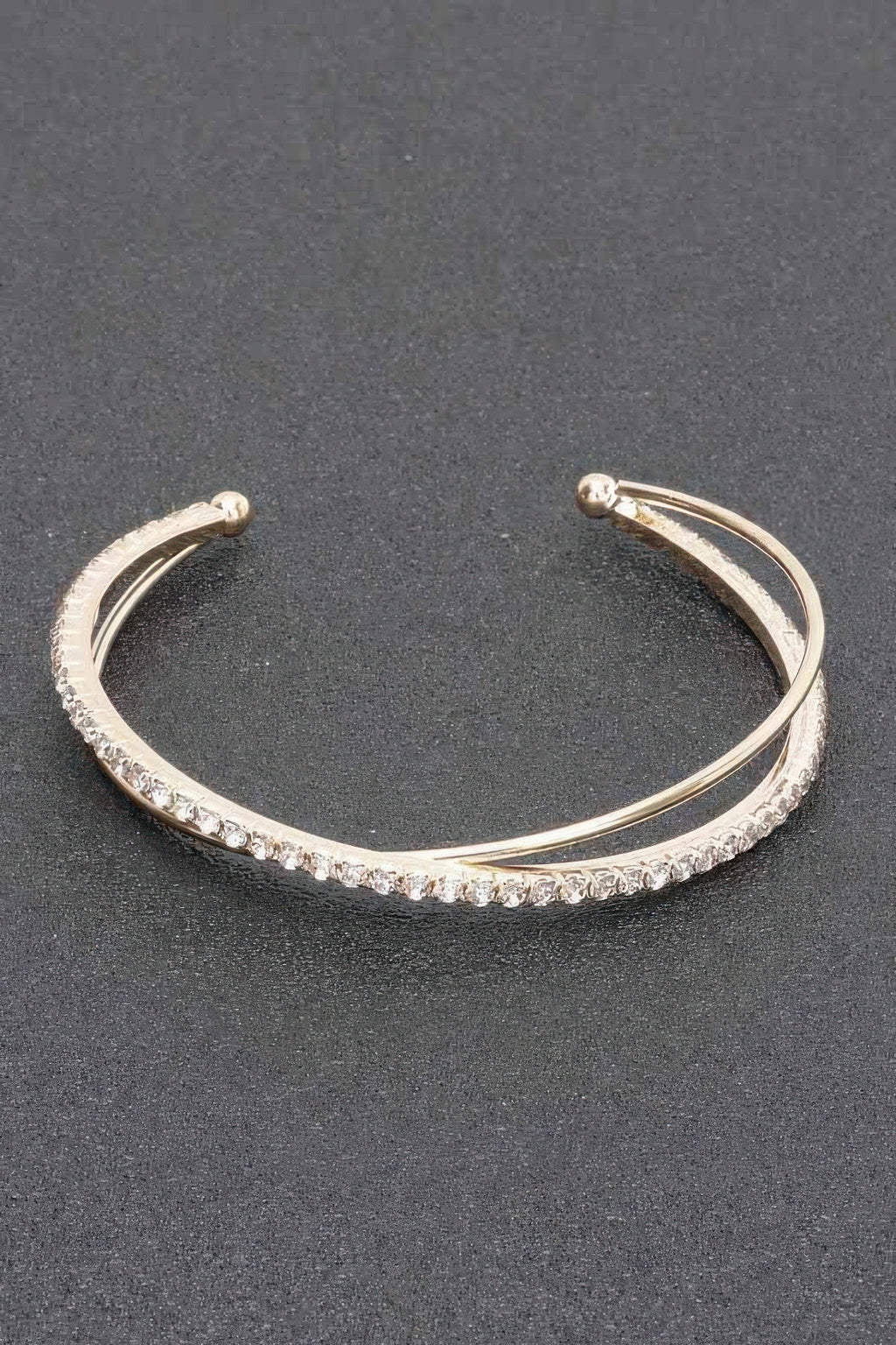 Gold-tone rhinestone cuff bracelet with a continuous sparkling row and round end caps