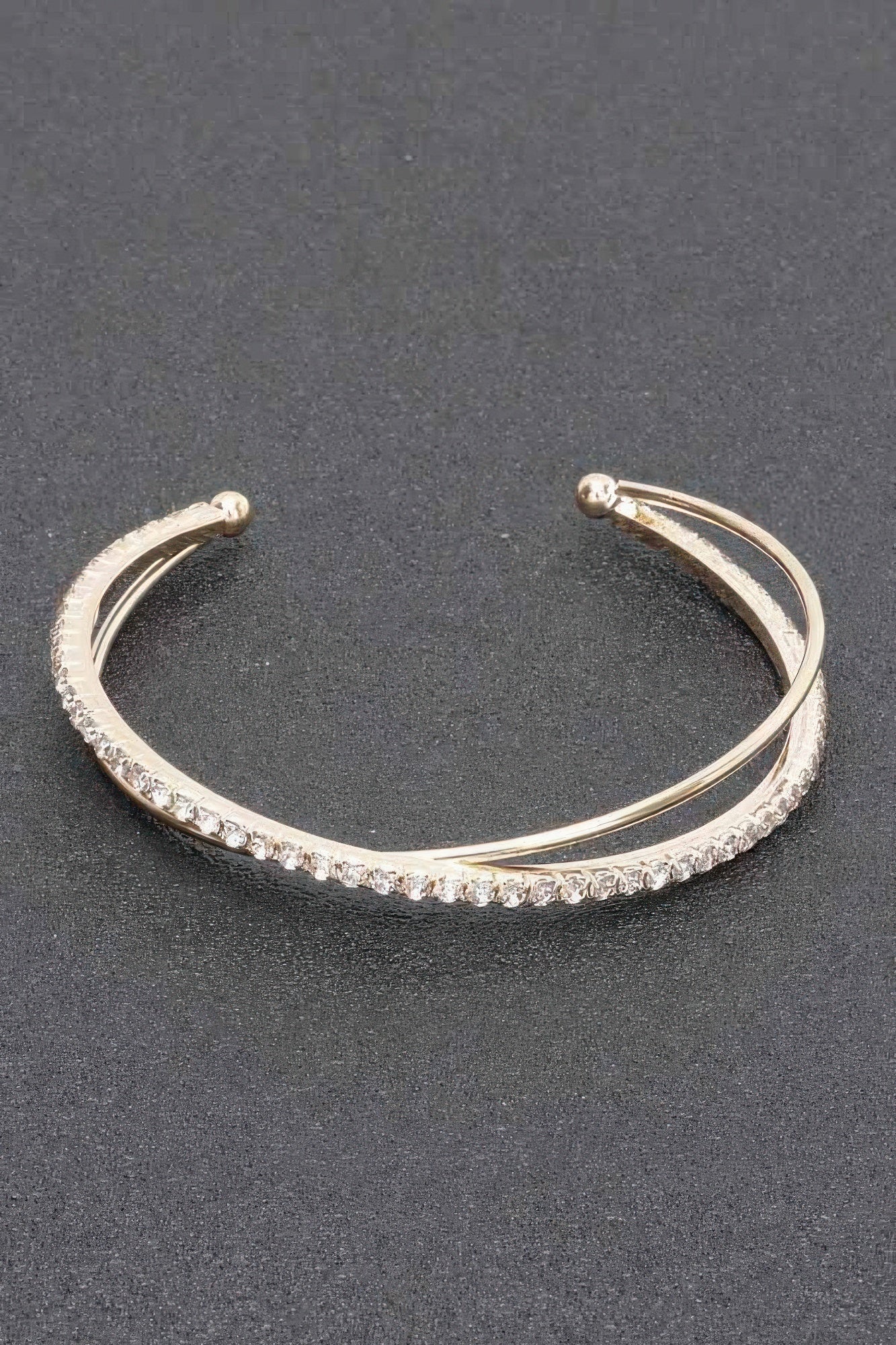 Gold-tone rhinestone cuff bracelet with a continuous sparkling row and round end caps
