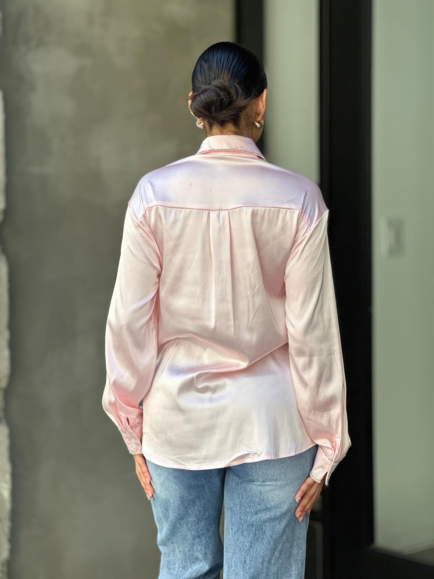 Back view pale pink satin blouse with long sleeves and rhinestone-trimmed yoke