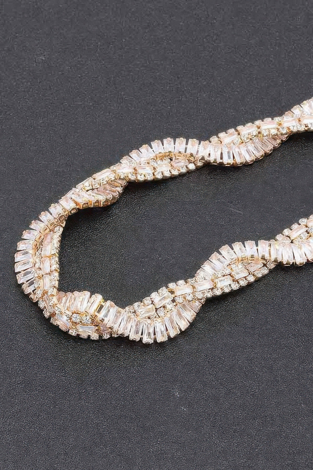 Close-up of clear rhinestone baguette links on a curved necklace band