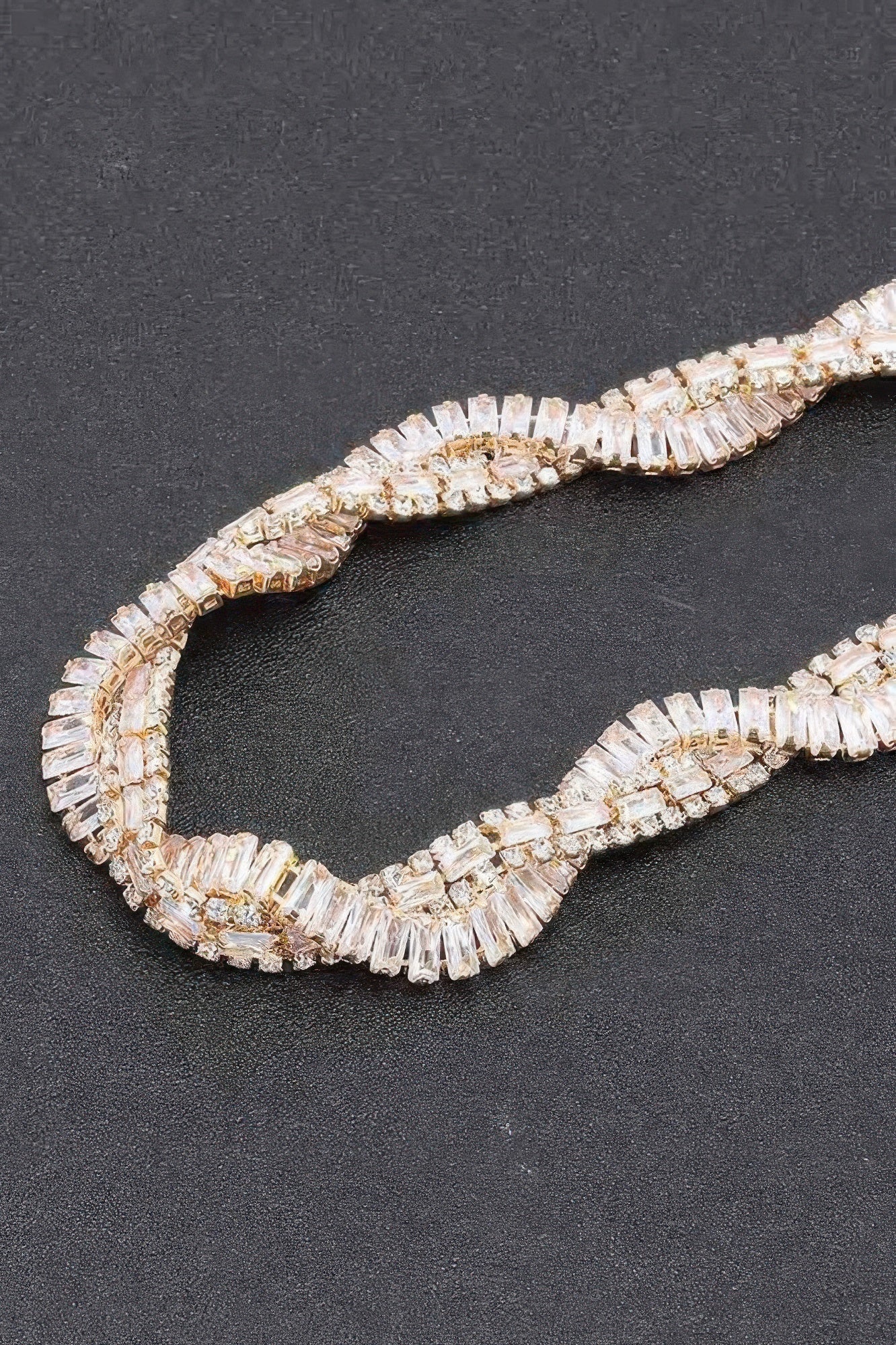 Close-up of clear rhinestone baguette links on a curved necklace band