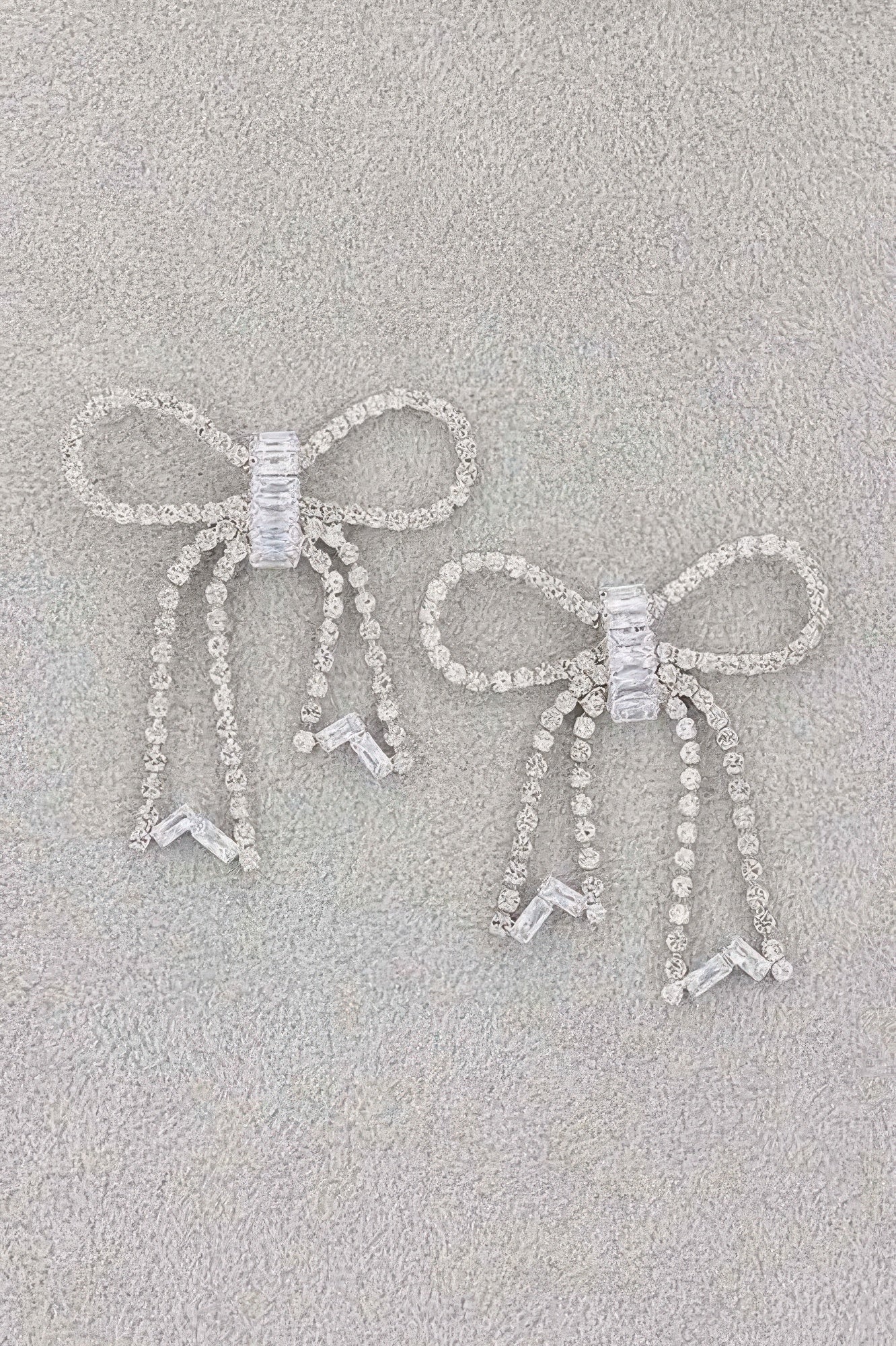 Rhinestone ribbon earrings with two bows, vertical chains, and bow-like charm drops, silver