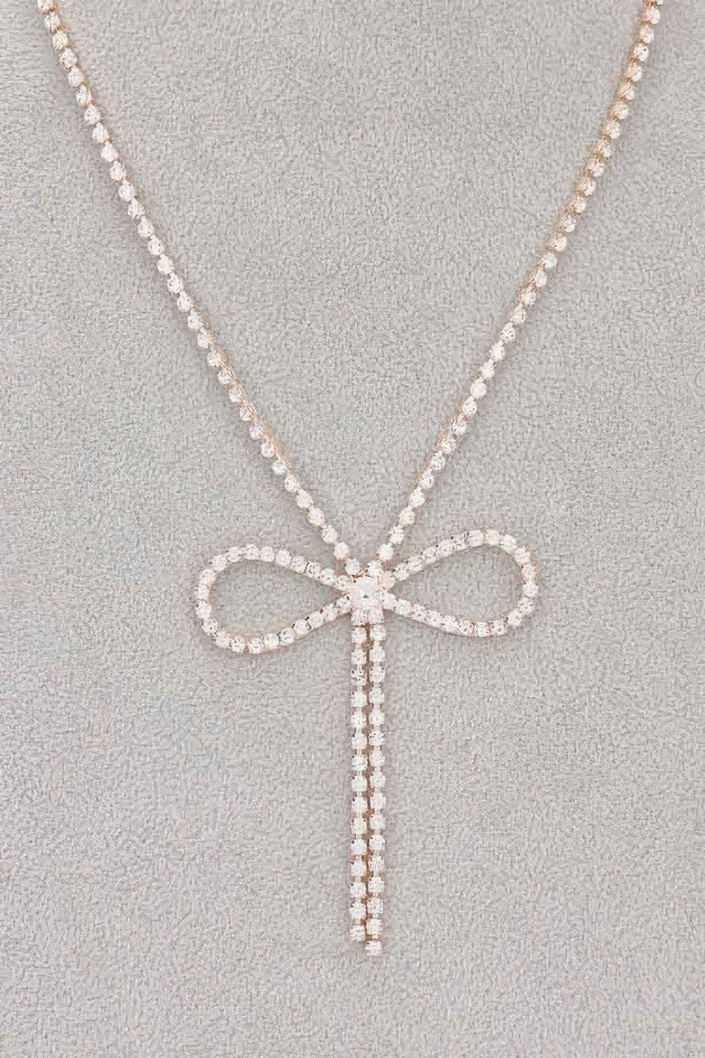 Rhinestone bow pendant with hanging ribbon strands on rhinestone chain