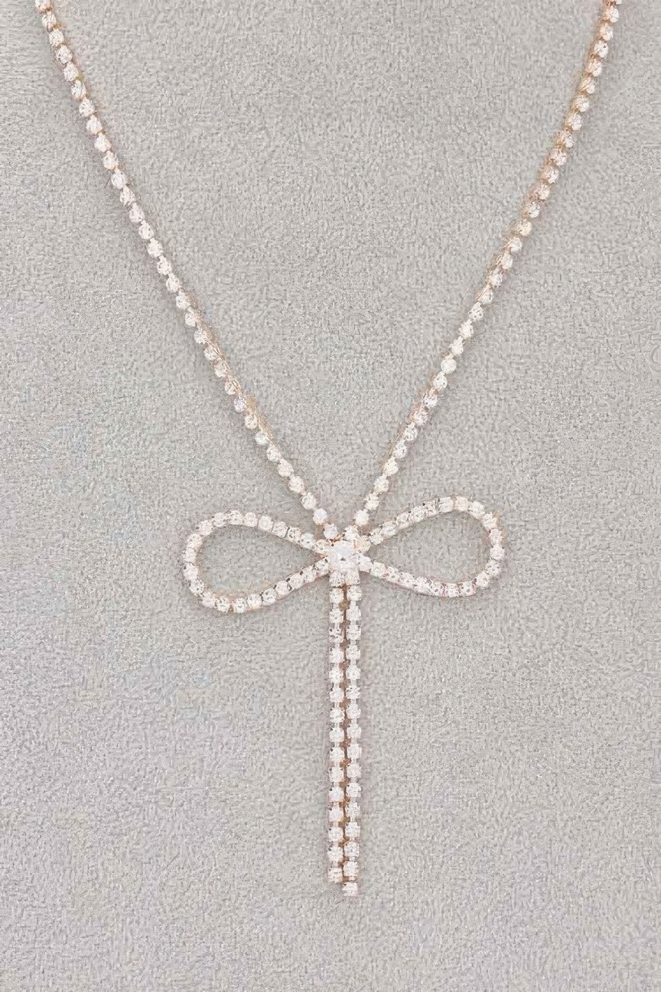 Rhinestone bow pendant with hanging ribbon strands on rhinestone chain