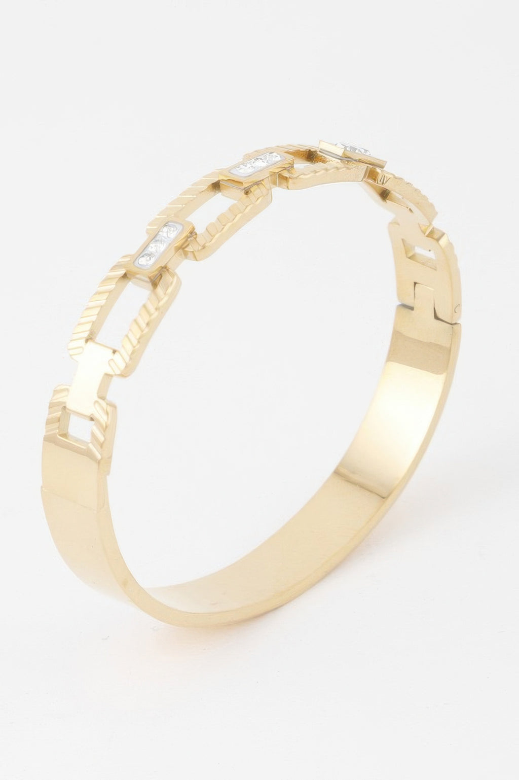 Close view of ribbed gold bracelet clasp and link detail with small clear stones