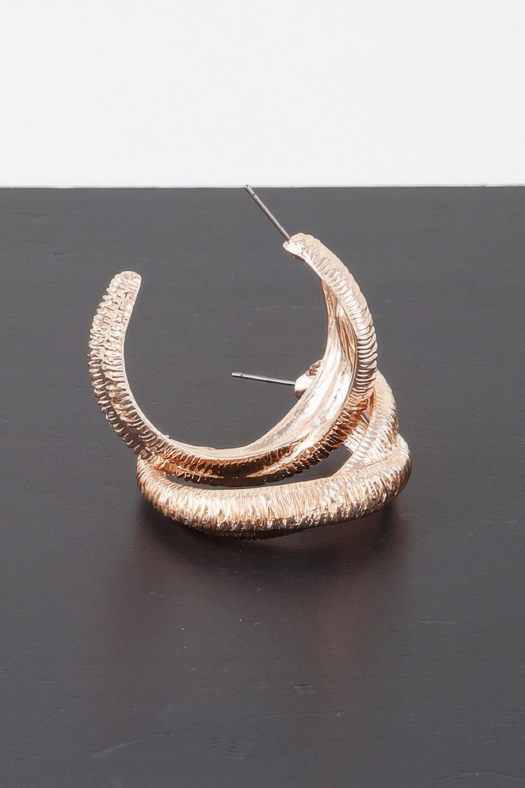 Gold-tone ribbed intertwined hoop earrings, close view of nested curved loops