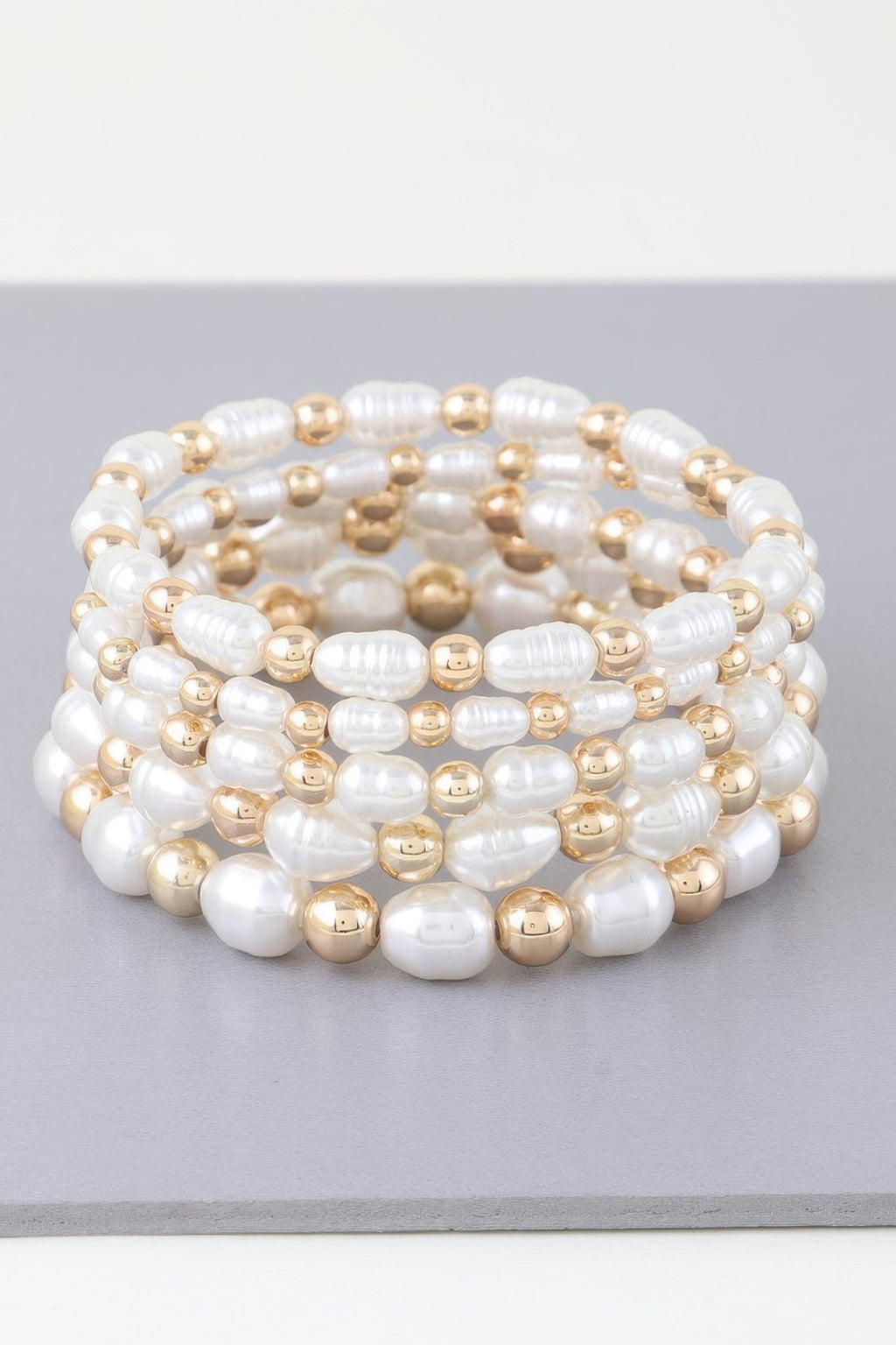Multi-strand pearl bead bracelet with gold-tone round accents, coiled on display
